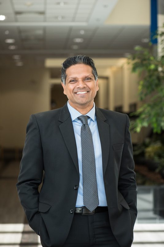 Arpan Nalin Patel, D.M.D., a dentist in Langhorne, Pennsylvania, photographed in a dark suit in an office lobby.